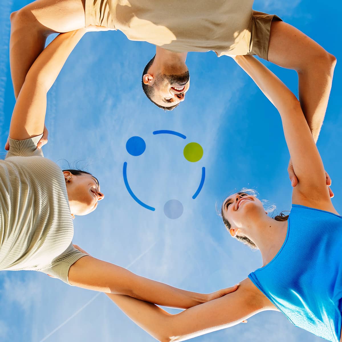 A young man and two young women are photographed from the ground, looking upwards. They stand in a circle, holding each other's shoulders. Above them, the blue sky with a few white clouds. The three are smiling at each other. In the center of the image, three dots with blue lines also form a circle.